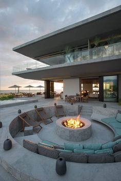 a fire pit in the middle of a patio with lounge chairs and tables around it