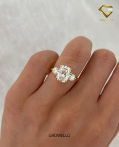 a woman's hand with a three stone diamond ring on top of her finger