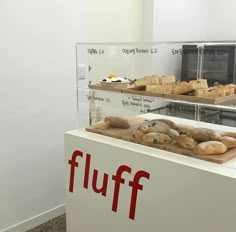 breads and pastries are on display in a bakery case with the word fluff written on it