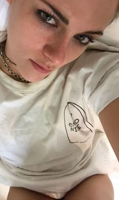 a woman laying on top of a bed wearing a white shirt and silver bracelets