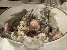 a white bowl filled with flowers on top of a table