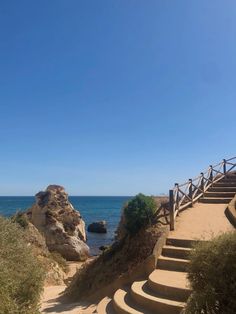 stairs lead down to the beach and into the ocean with large rocks in the background