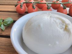 a white bowl filled with cheese next to tomatoes