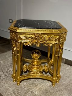 an ornate gold and black marble topped end table on carpeted area with white wall in background