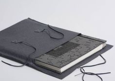 an open book is sitting on top of a gray cloth cover with black string attached to it