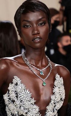 a woman with dark skin wearing a necklace and dress