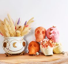 there are three skulls in a vase on the shelf next to some flowers and feathers