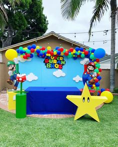 an outdoor birthday party setup with balloons, stars and mario bros balloon arch on the lawn