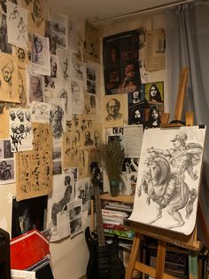 an artist's studio with various drawings and paintings on the wall, including a guitar