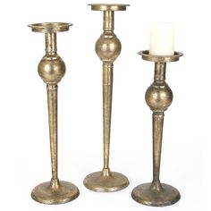 two brass candlesticks are standing next to each other with a candle in the middle