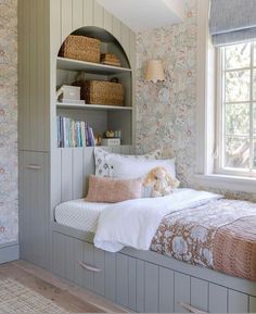 a bed sitting under a window next to a book shelf