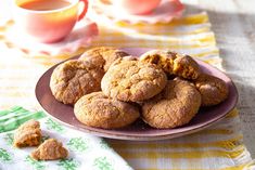 a plate full of cookies on top of a table next to a cup of tea