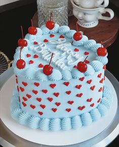 a blue and white birthday cake with cherries on it