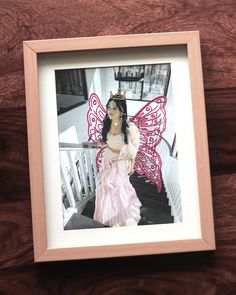 a framed photo of a fairy with pink wings