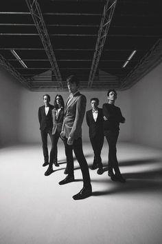 a group of men standing in an empty room with one man looking at the camera