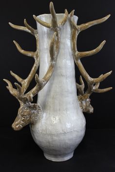 a white vase with antlers sticking out of it's sides on a black background