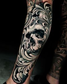 a man's leg with a skull and flowers tattoo design on the calf sleeve