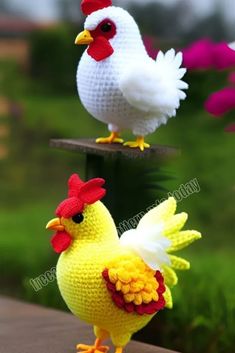 two crocheted chickens sitting on top of a wooden table next to each other