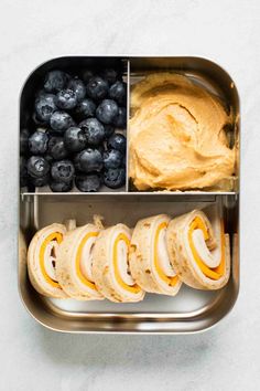 an open lunch box with blueberries, bread and hummus