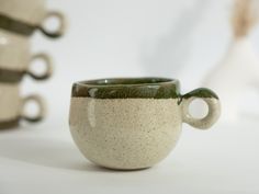 two coffee mugs sitting next to each other on a white counter top, one has a green handle