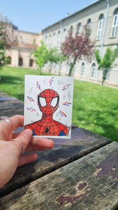 a person holding up a card with a spider man drawn on it