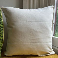 a white pillow sitting on top of a window sill next to a yellow chair