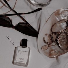 a bottle of perfume sitting on top of a table next to sunglasses