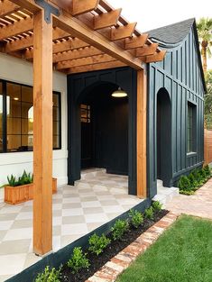 a black and white house with wooden pergols on the front porch, covered in wood