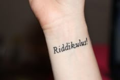 a woman's wrist tattoo with the word riddakus written in black ink