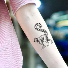 a woman's arm with a tattoo on it that has a raccoon on it