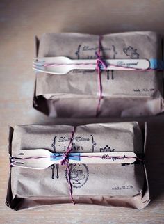 three wrapped packages tied with twine on top of a wooden table