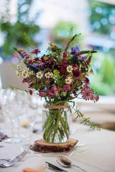 a vase filled with purple and white flowers sitting on top of a table next to silverware