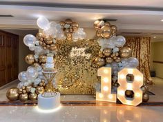 balloons and lights decorate the entrance to a party with gold, white and silver decorations