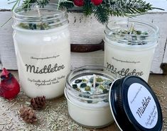 three jars filled with candles sitting on top of a table next to pine cones and flowers