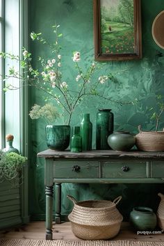 green vases are sitting on a table in front of a painting and other items