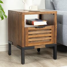 a nightstand with a book on it next to a couch and coffee cup in the corner