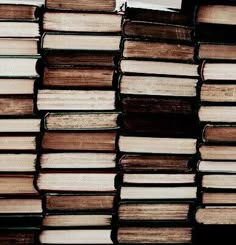 a stack of books sitting next to each other on top of a wooden table covered in lots of brown and white books