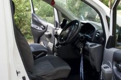 the interior of a small white van with its door open and steering wheel in view