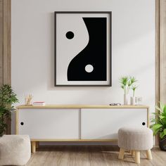 a living room with a white and black painting on the wall next to two stools