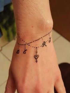 a woman's hand with a small tattoo on the wrist and heart charms attached to it