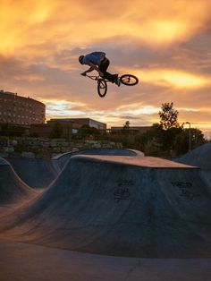 a man flying through the air while riding a bike on top of a skateboard ramp