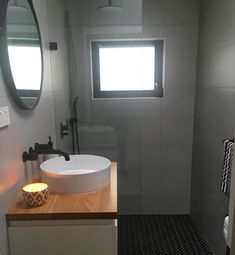 a white sink sitting next to a window in a bathroom on top of a wooden counter