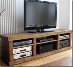 a flat screen tv sitting on top of a wooden entertainment center next to a window