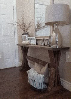 a wooden table sitting in the middle of a living room next to a lamp and mirror