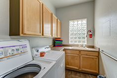 a washer and dryer in a small room with wood cabinets on the walls