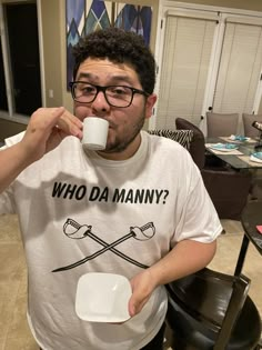 a man sitting at a table drinking from a cup