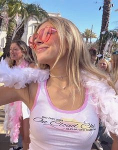 a woman wearing pink and white is posing for the camera with feathers around her neck