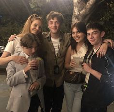 a group of people standing next to each other near a tree in the night time