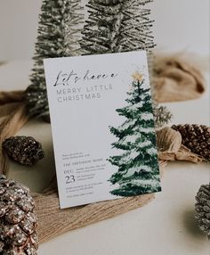 there is a christmas card on the table with pine cones and other decorations around it