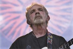 a man holding a white guitar in his right hand